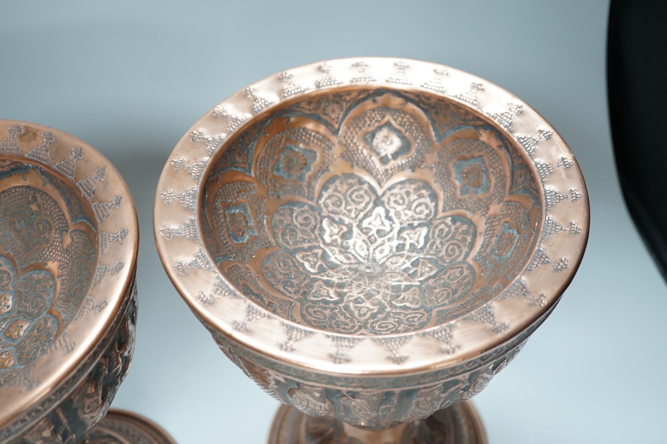 A pair of Persian copper figural decorated chalices, 27cms high